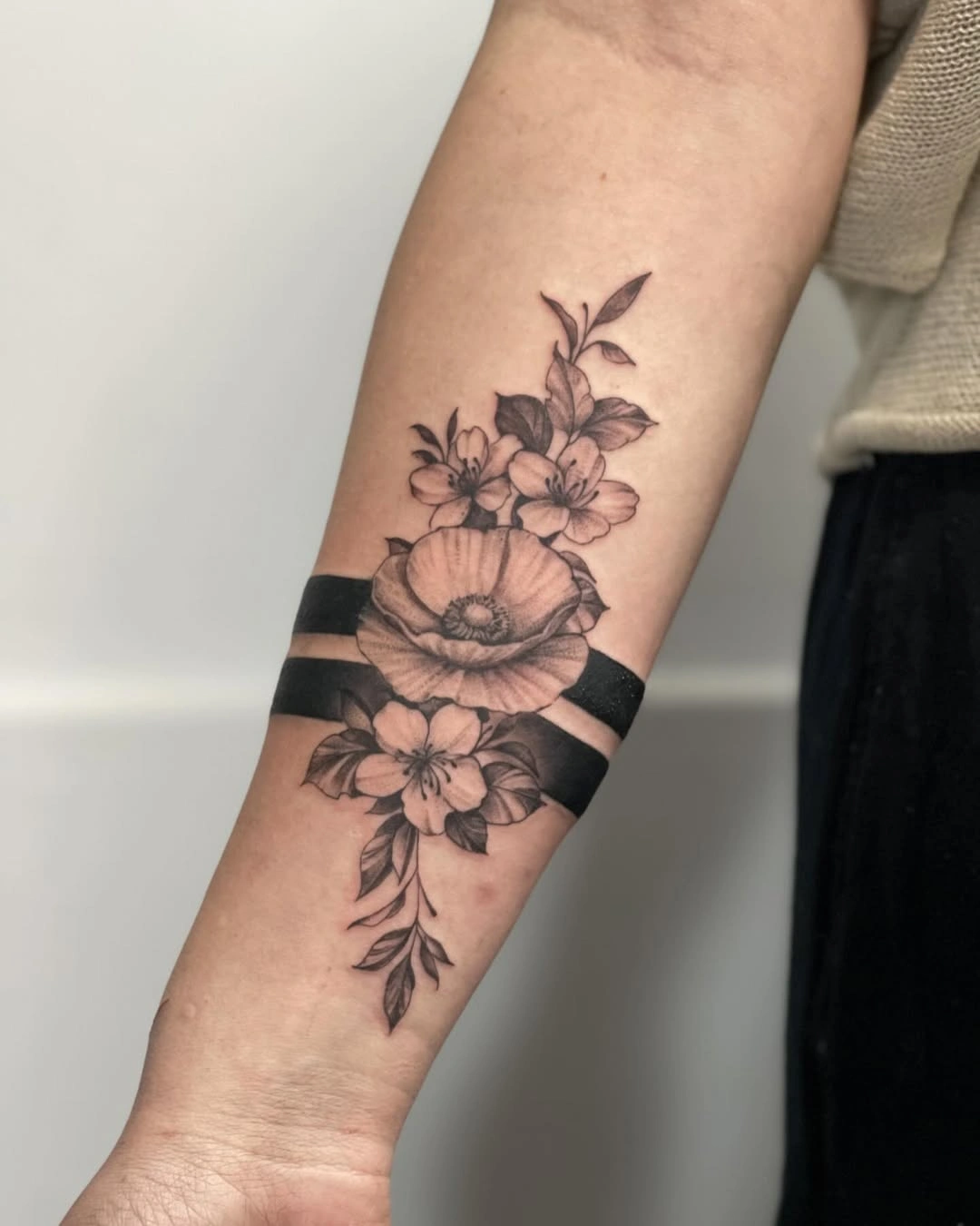 Tatuaj cu flori și benzi negre pe antebraț