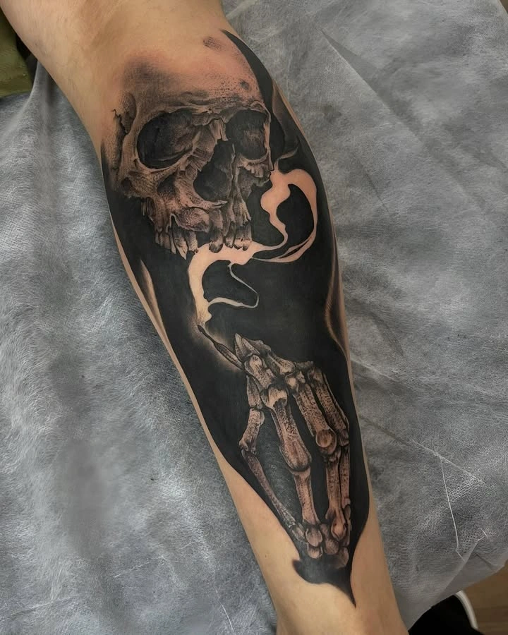 Tatuaj detaliat cu un craniu și o mână scheletică pe un fundal întunecat