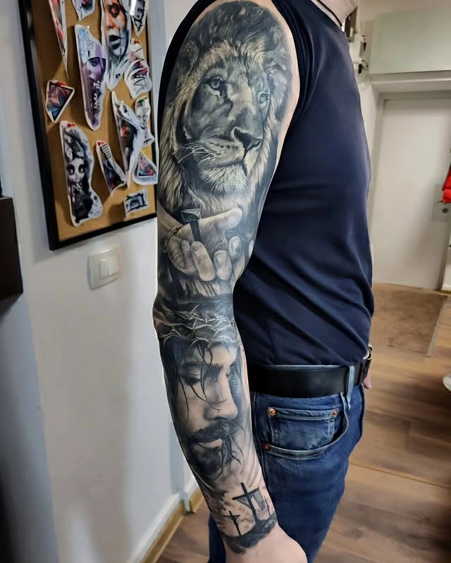 Tatuaj complex cu un leu și un portret realist pe brațul unei persoane