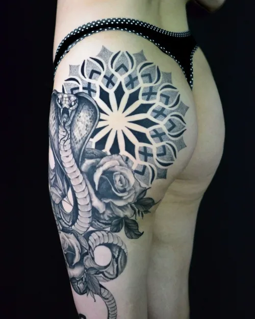 Tatuaj mare alb-negru pe șold și coapsă, cu cobră realistă, trandafiri și mandala geometrică cu dotwork.